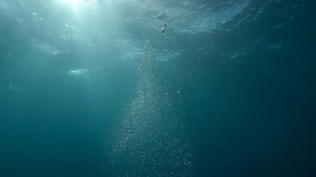 Peaceful underwater scene with sunlight and streaming bubbles in the ocean.